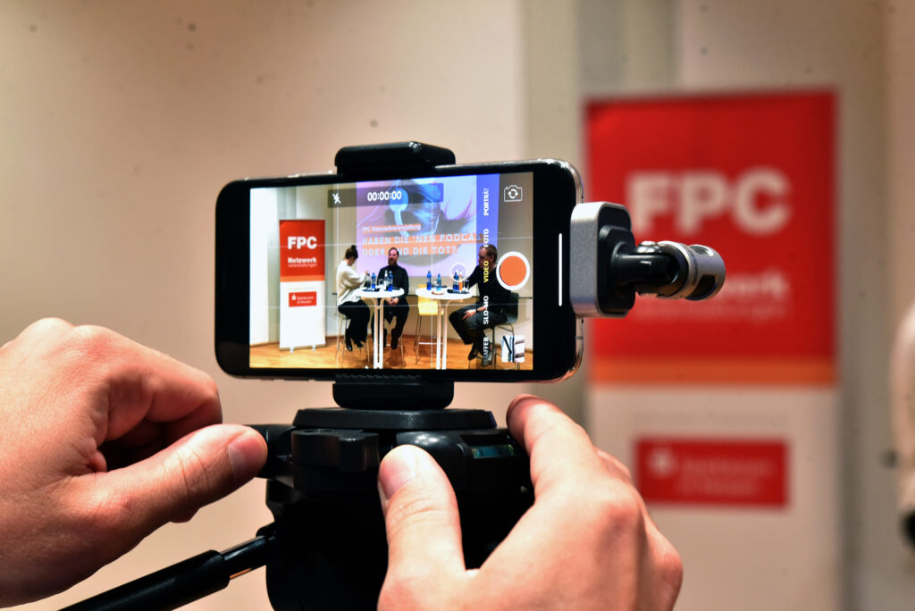 Symbolfoto von einer Veranstaltung des Frankfurter PresseClubs e.V., die live über ein Smartphone gestreamt wird.